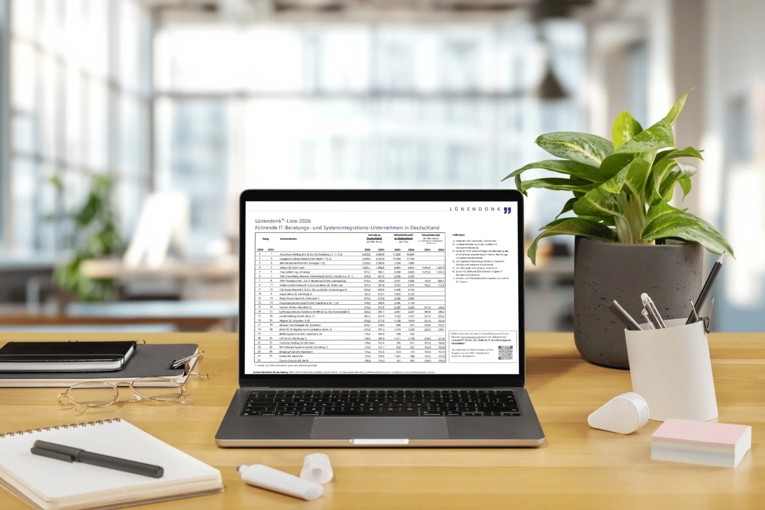 Laptop auf einem hellen Büroschreibtisch zeigt die Lünendonk®-Liste 2026 der führenden IT-Beratungs- und Systemintegrations-Unternehmen in Deutschland. Im Hintergrund ein modernes, offenes Büro. Neben dem Laptop befinden sich eine Topfpflanze, ein Stiftehalter, ein Notizbuch, eine Brille und Haftnotizen.